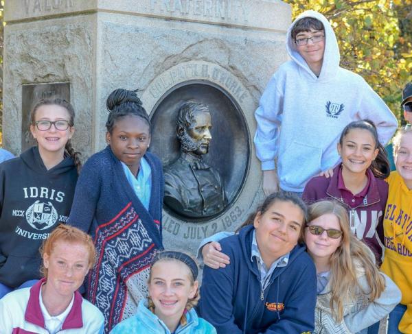 Students post with their teacher in front of a marker at Gettysburg.