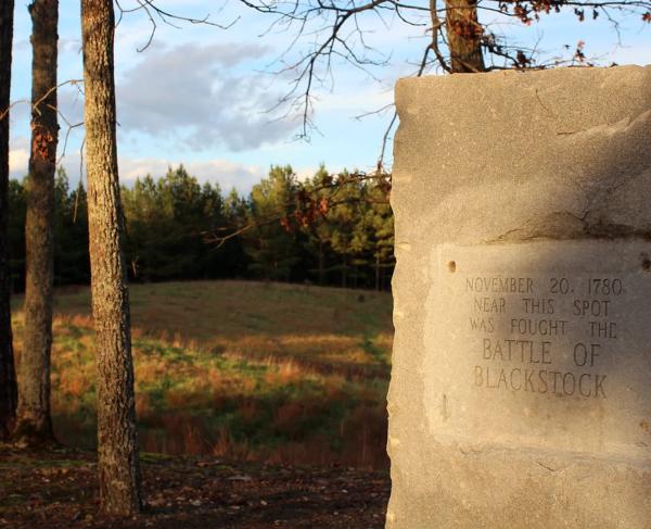 Photograph of a battlefield with a stone marker in the foreground. 