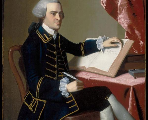 Portrait of a man sitting at a writing desk holding a quill pen and a book.