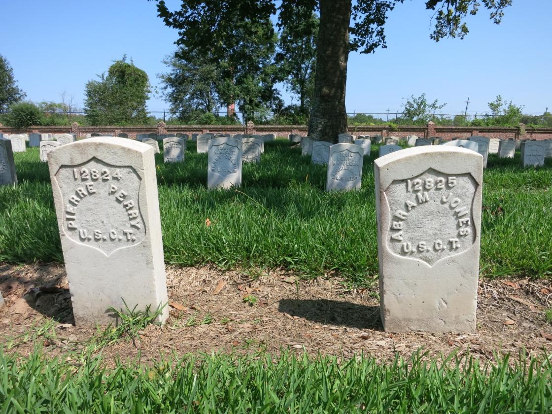 Photo shows two graves of US Colored Troops (USCT) who died during the US Civil War. The location is the Chalmette National Cemetery in New Orleans, Louisiana. The view is toward the southeast.